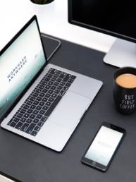 laptop, coffee mug, and iPhone on desk
